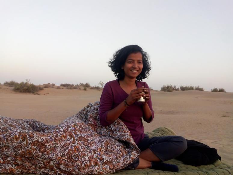 woman on bed in desert with tea in hand
